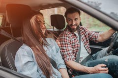 Ładni i rozochoceni ludzie siedzą w samochodzie i jazdie tam Facet jedzie mnie i trzyma jego ręki na rudder i fotografia stock Ładni i rozochoceni ludzie siedzą w samochodzie i jazdie tam Facet jedzie mnie i trzyma jego ręki na rudder i fotografia stock